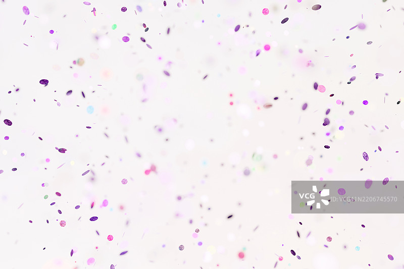 粉色和紫色的纸质五彩纸屑洒落在白色背景上。庆祝圣诞快乐、新年快乐和生日的节日概念。也非常适合用于黑色星期五促销产品的展示。图片素材