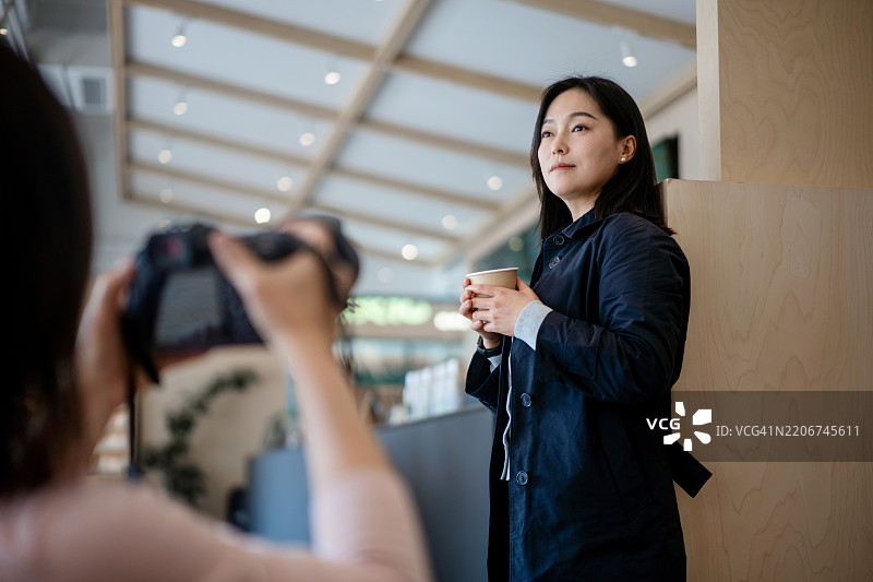 一位女性在咖啡店内为摄影师摆姿势图片素材