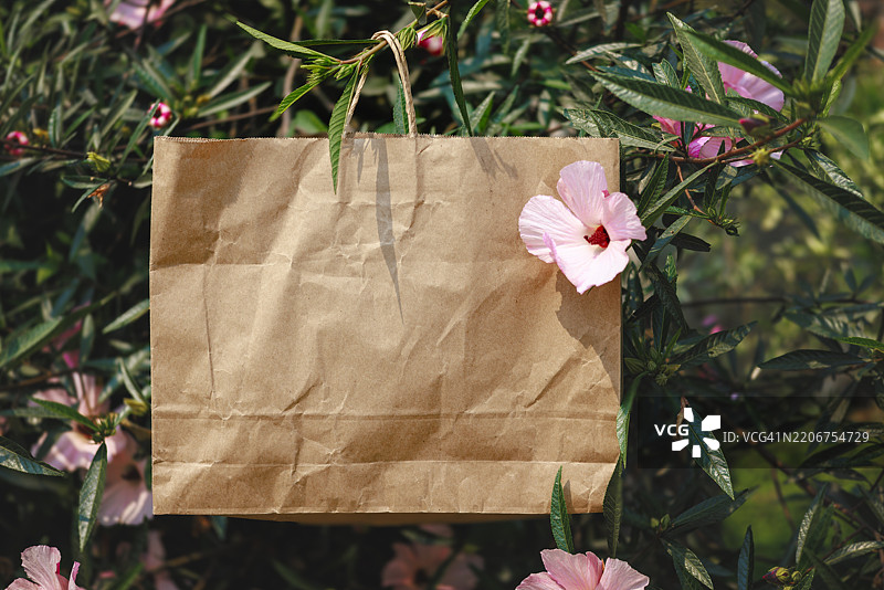 环保的棕色纸袋悬挂在绿植之间图片素材