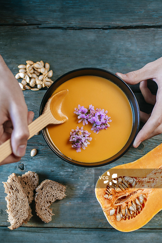 手握勺子盛着南瓜汤的特写镜头图片素材