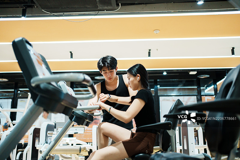 健身学员们开始进行器械训练，教练在旁边观察。图片素材