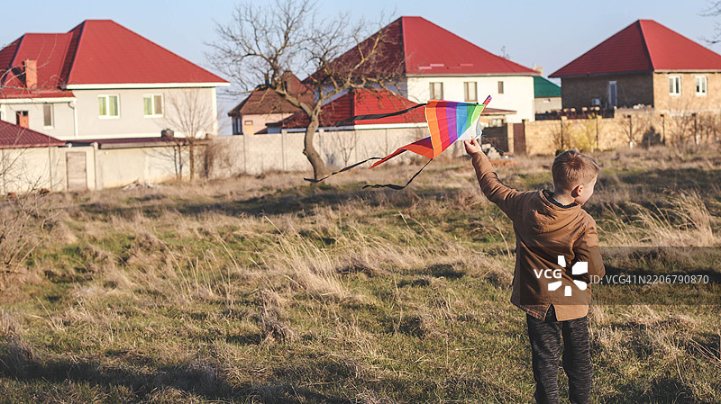 一个男孩在乡村房屋附近的清新空气中放风筝图片素材