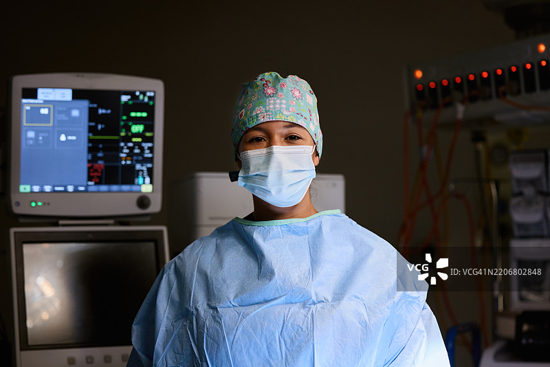 自信的外科医生戴着口罩，靠近医疗设备图片素材