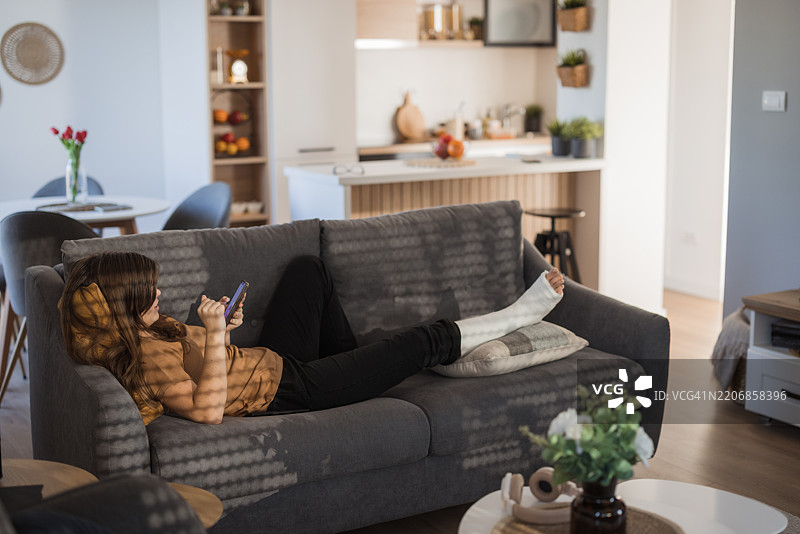 戴着石膏的女孩在休息并使用手机图片素材