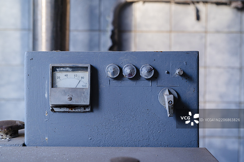 一台旧工业机器的控制面板，展示了岁月的磨损和在被遗忘的车间中的灰尘。图片素材