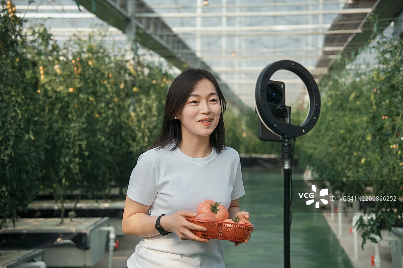 亚洲女性农民正在用手机进行直播图片素材