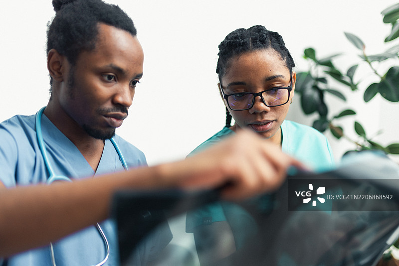 两位医生在现代临床环境中分析X光图像以作出诊断。图片素材