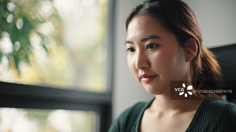 亚洲女性在使用笔记本电脑。图片素材