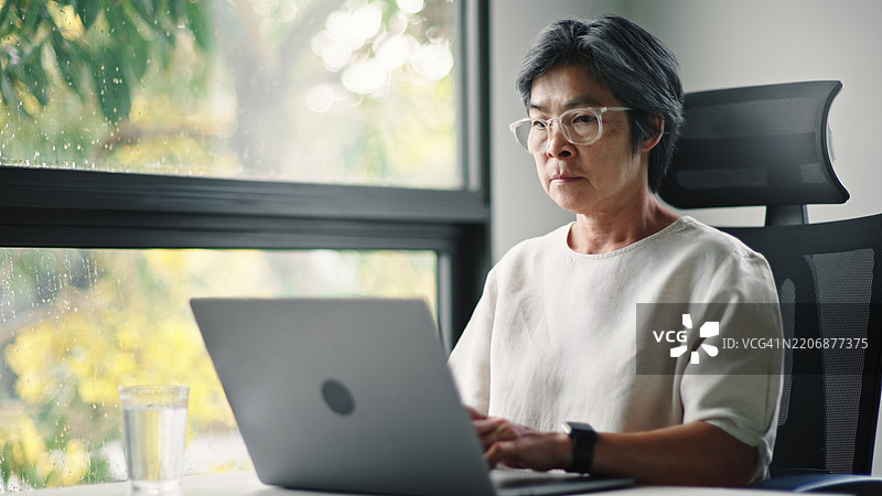 成熟的女商人在使用笔记本电脑。图片素材