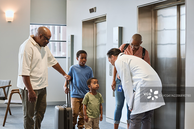 医生在医院电梯旁与男孩及其家人交谈图片素材