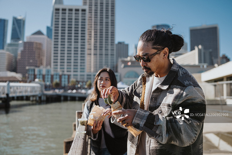 一对情侣在加利福尼亚州旧金山的海滨探索时享用街头美食图片素材