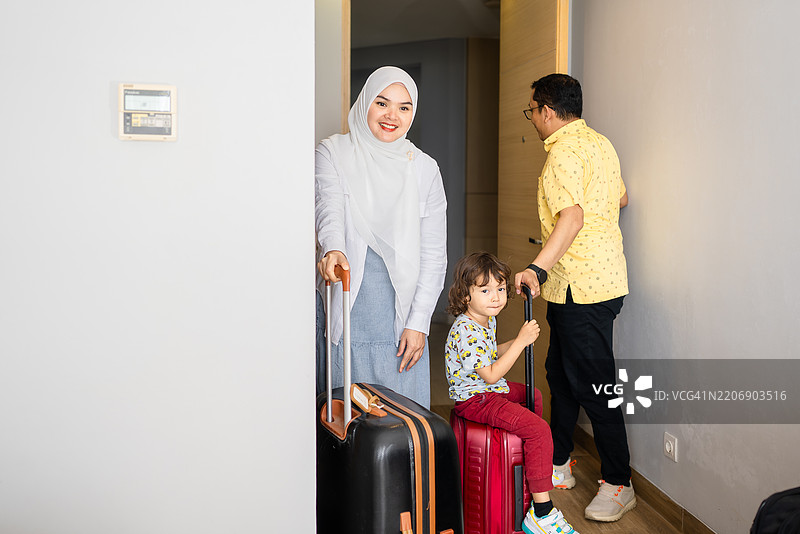 快乐的年轻家庭带着一个孩子走进豪华酒店的房间图片素材