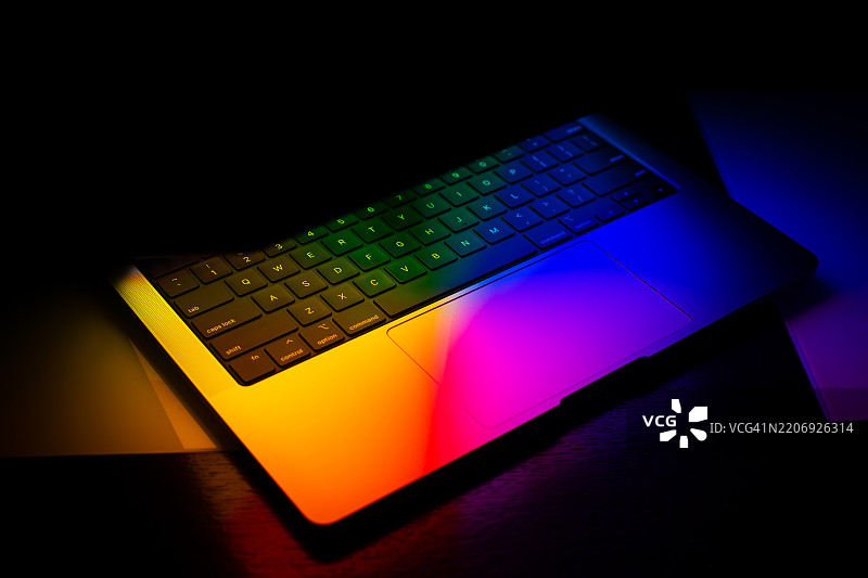 黑色背景下紫色霓虹灯照亮的笔记本电脑屏幕图片素材