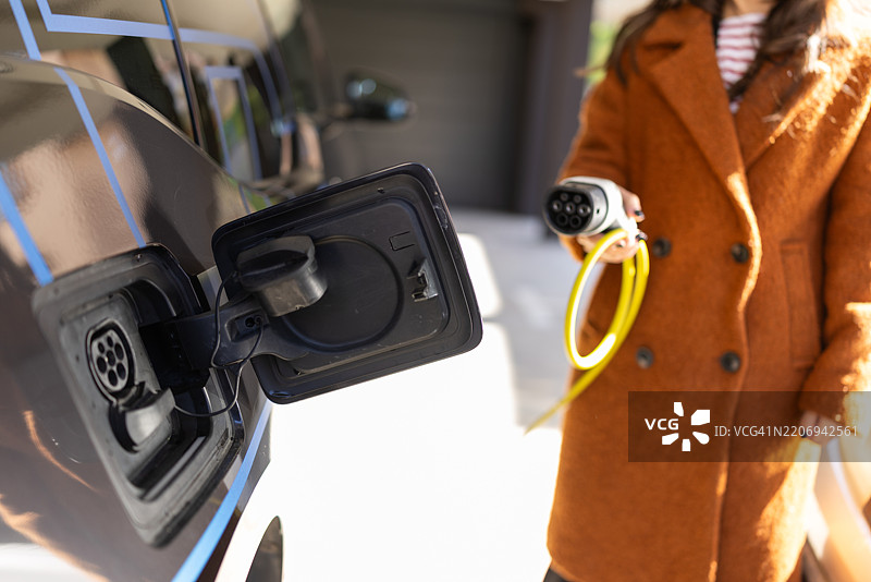 女性正在为电动车充电图片素材