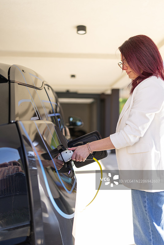 女性正在为电动车充电图片素材