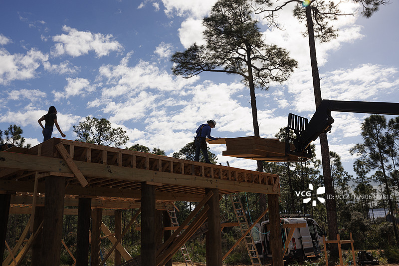 建筑工人在住宅施工现场从叉车上卸下一块胶合板图片素材