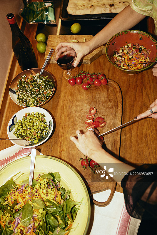 高角度视图的女性朋友们在家中互相帮助准备食物图片素材