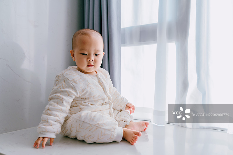 婴儿独自在窗台上玩耍；亚洲家庭生活方式图片素材