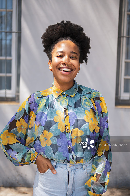 一位拉丁裔女性自信地站在户外，穿着时尚的服装，阳光明媚的日子里，她正看着镜头。图片素材