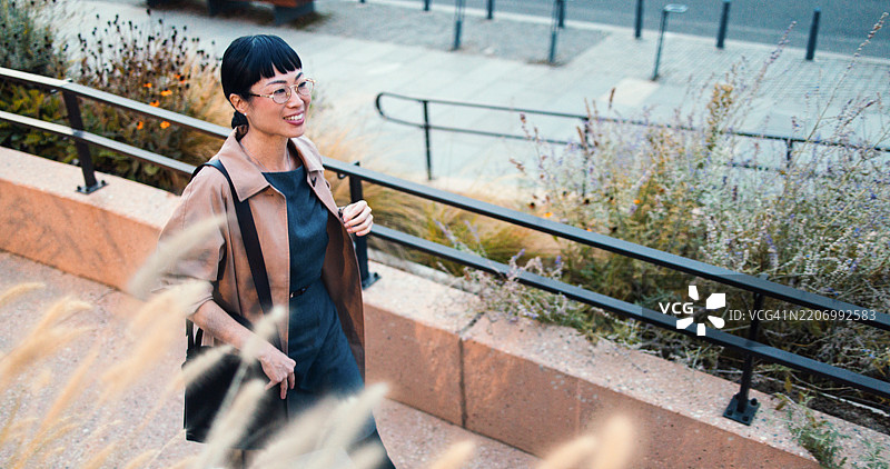 阳光明媚的日子里，女商人在城市街道上行走图片素材