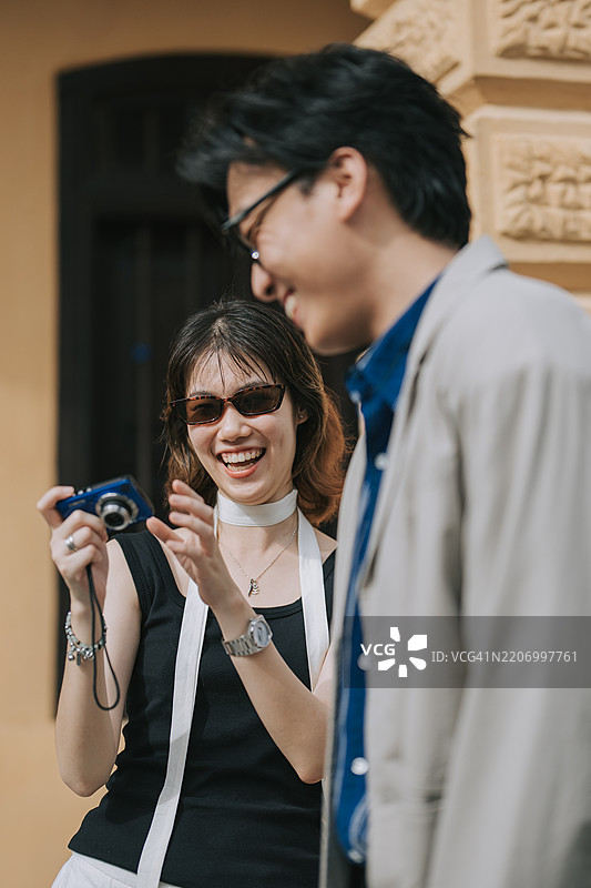 亚洲华裔年轻情侣在槟城的周末早晨享受用傻瓜相机拍照的乐趣图片素材
