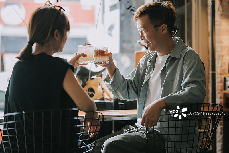 亚洲华人情侣在窗前举杯庆祝，享受周末早晨的咖啡时光。图片素材