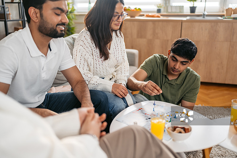 一群印度和穆斯林朋友在沙发上一起玩飞行棋游戏图片素材
