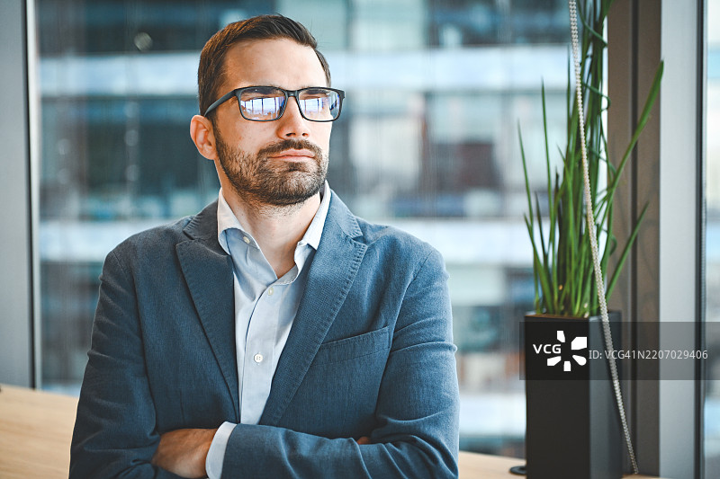 年轻男商人在商务西装前景中，背景是办公大楼。图片素材