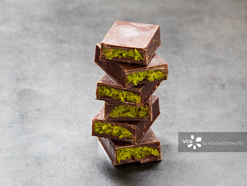 现代迪拜巧克力。巧克力内填充酥脆的卡塔伊菲和翡翠绿的开心果酱。深色背景。特写。图片素材