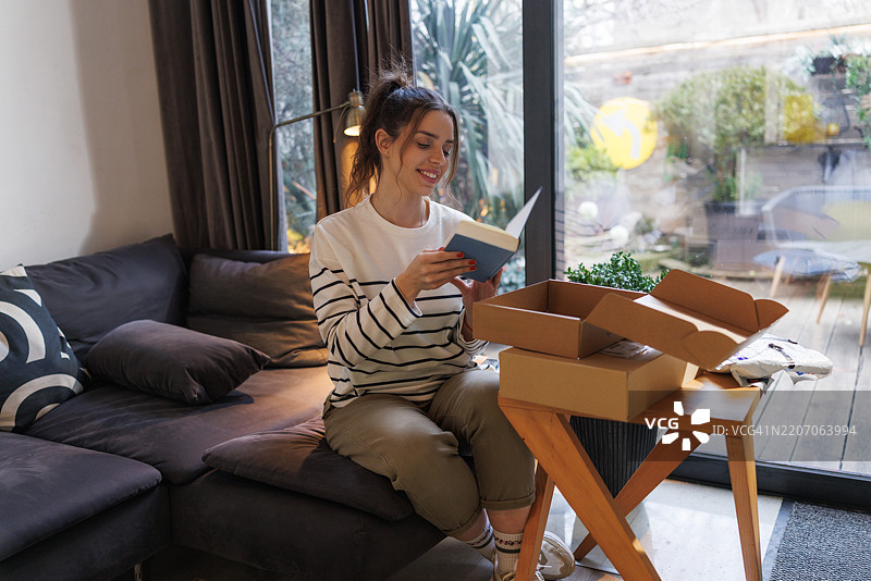 微笑的女性在阳光明媚的窗边拆包裹图片素材