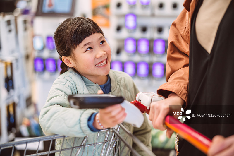 快乐的小女孩和家人在杂货店结账时购物图片素材