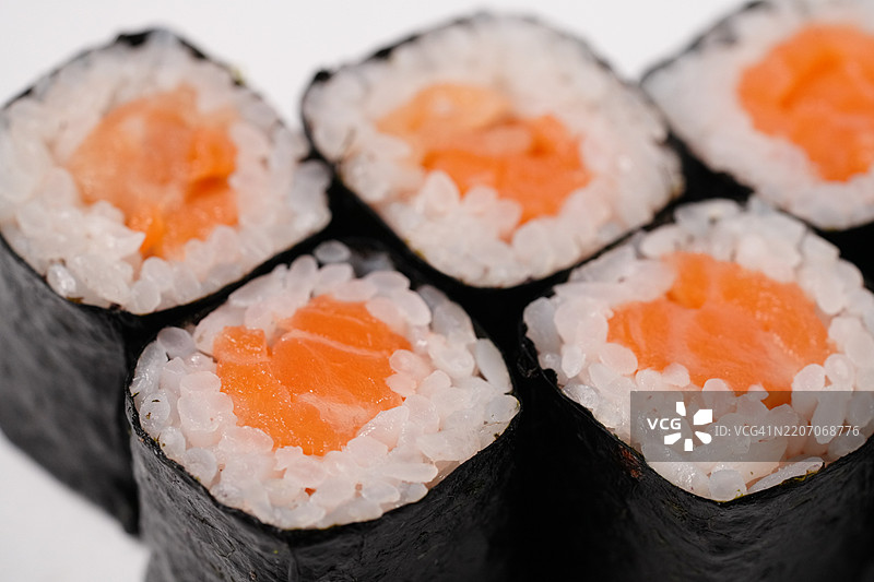 新鲜三文鱼馅的卷寿司特写，背景为白色图片素材