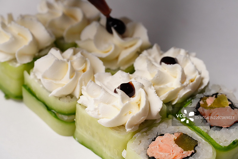 厨师用奶油奶酪和酱油装饰寿司卷图片素材