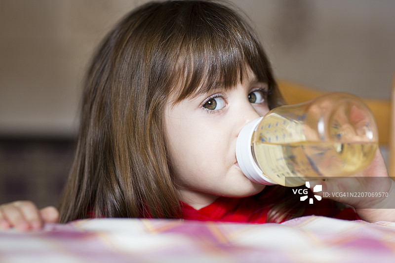年轻女孩在温馨的家中喝水瓶里的饮料图片素材