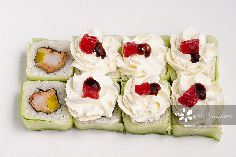 白盘上的寿司卷，配有黄瓜、虾、奶油奶酪、胡椒和照烧酱图片素材