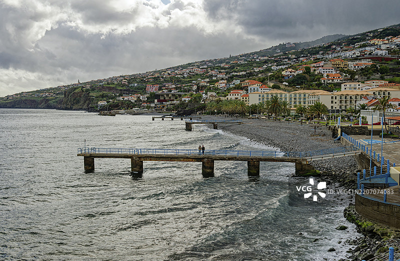 在葡萄牙马德拉圣克鲁斯市的大西洋海滩上，雨天的散步。图片素材