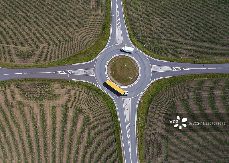 无人机拍摄的图像，环形交叉口上有卡车穿梭于收割后的田野之间，阿斯滕，林茨地区，上奥地利，奥地利，欧洲图片素材