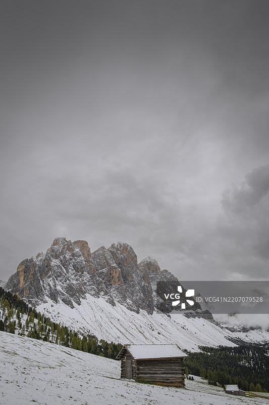 从甘本维泽（Gampenwiese）俯瞰盖斯勒山脉的一部分，前景是一座阿尔卑斯小屋，意大利南蒂罗尔的多洛米蒂山脉，普兹-盖斯勒自然公园，圣玛德琳娜，富内斯，维尔诺斯塔尔，欧洲，雪景。图片素材
