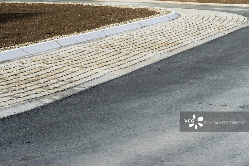 触觉铺路砖引导行人，连接沥青道路和混凝土路缘，靠近土壤区域，德国北莱茵-威斯特法伦州博特罗普，欧洲图片素材