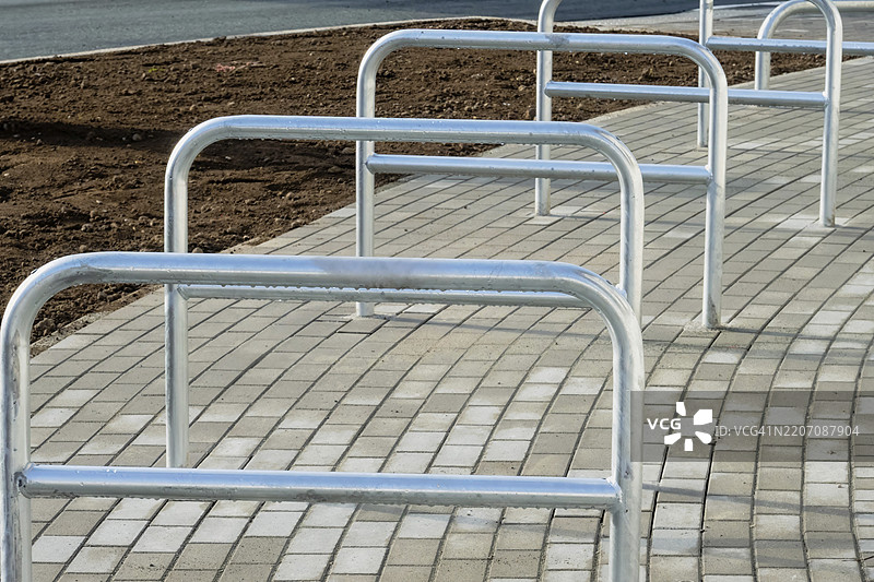 崭新的自行车架在混凝土铺石上准备好迎接自行车，位于德国北莱茵-威斯特法伦州的博特罗普，附近有一块泥土区域。图片素材