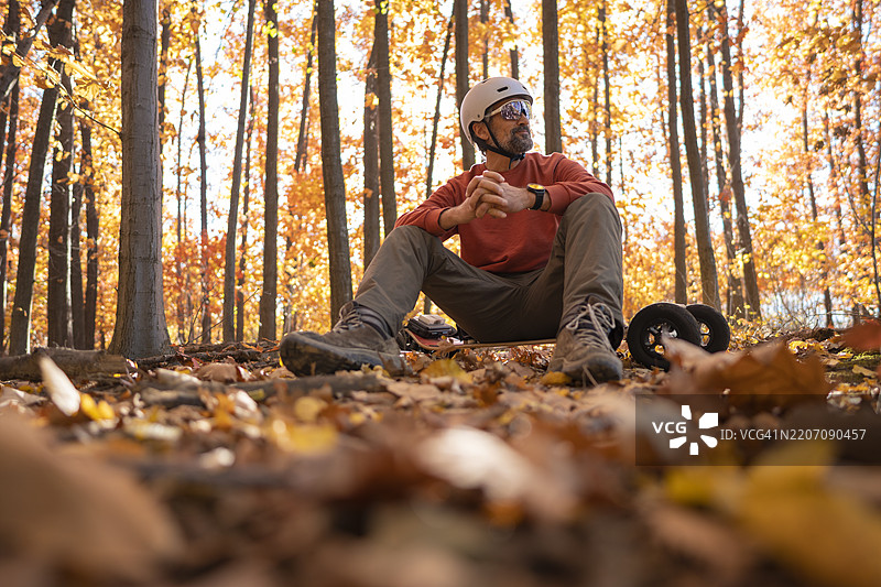 男子在秋季森林的日落时分放松，骑在电动山地滑板上图片素材