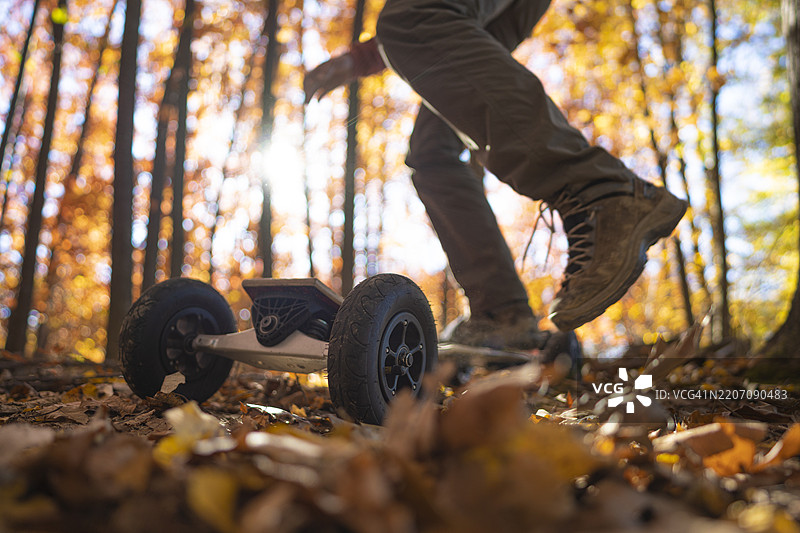 爱好与运动。男子在秋季森林的日落时分准备骑山地滑板图片素材