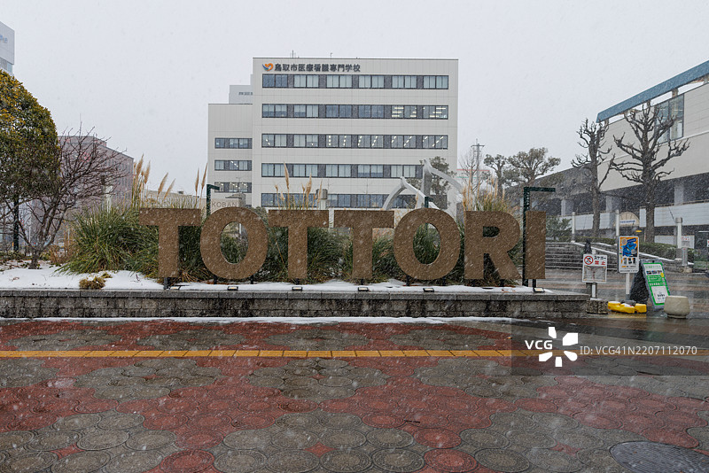 车站旁的鸟取标志上用英语写着“totottori”，冬天正在下雪。图片素材