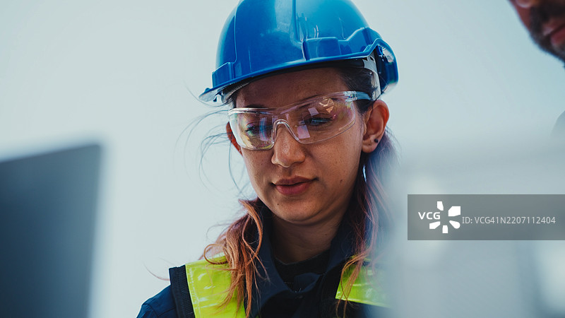 工程师在户外连接电气系统。两名穿着防护服的电工正在检查太阳能发电厂的电压。图片素材