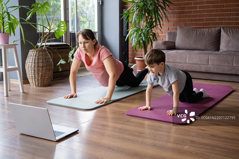 母亲和小儿子在家做运动，观看在线教程图片素材