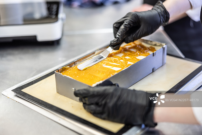 面包师的手正在准备甜点，用刮刀涂抹焦糖糖霜图片素材