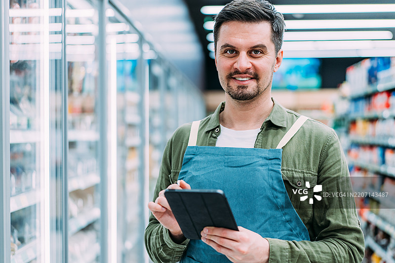 快乐的男性超市经理微笑着看向镜头。图片素材