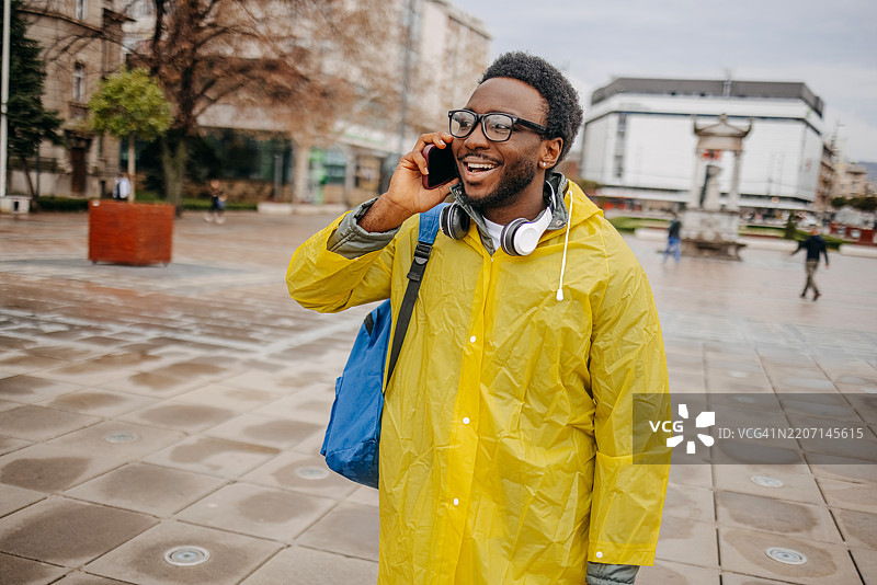 男人在雨天走在户外上班，同时在打手机。图片素材
