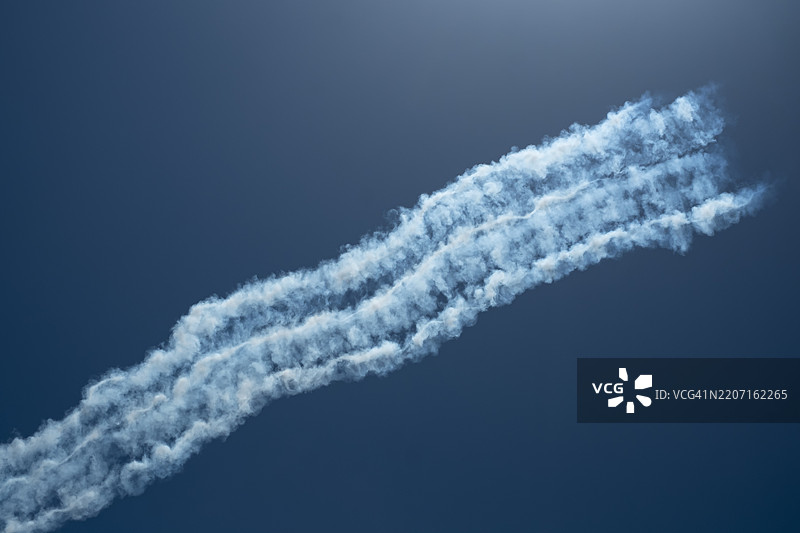 战斗机在蓝天中机动后留下的烟雾轨迹图片素材