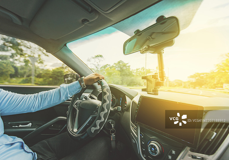 车内视角，一名男子正在驾驶汽车，双手握住方向盘。图片素材